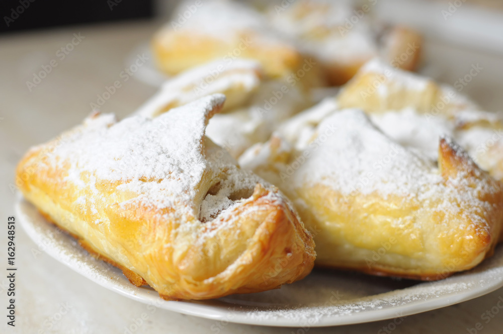 puffs with apple jam and sugar powder on a white plate