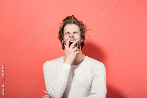 sleepy yawning man with long uncombed hair, morning wake up