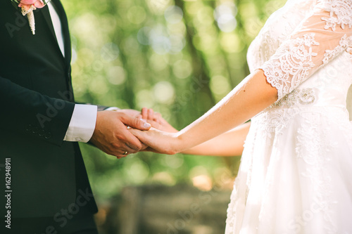 Loving couple holding hands with rings against wedding dress © jul14ka