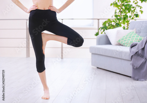 Beautiful young girl in black yoga wear in the room