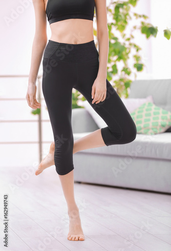 Beautiful young girl in black yoga wear in the room