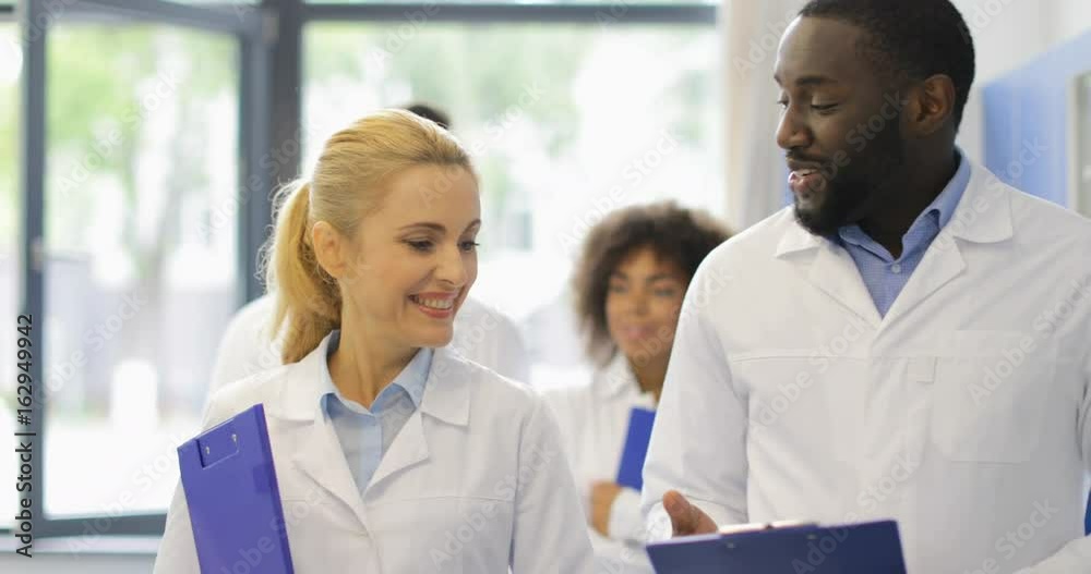 Group Of Scientists Discuss Document With Experiment Result While Walking In Modern Laboratory Communicating Slow Motion 60