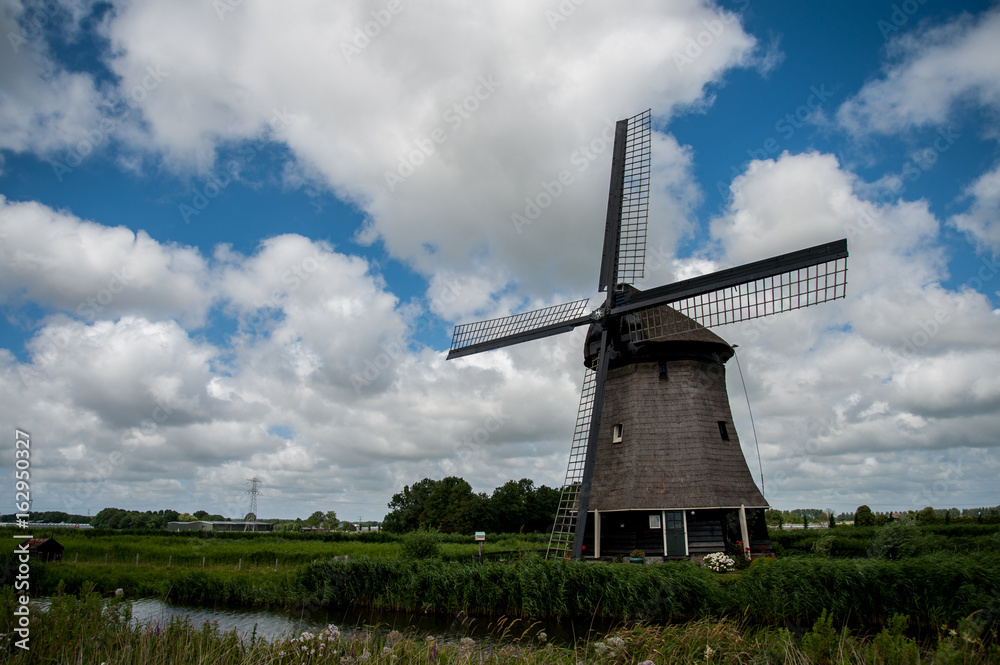 Dutch windmill with cloudy sky in the summer Dutch windmill with cloudy sky in the summer