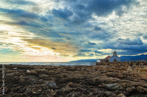 White little Church on shore of the sea of Crete  Greece. Early morning   the break in the rain clouds in the sky