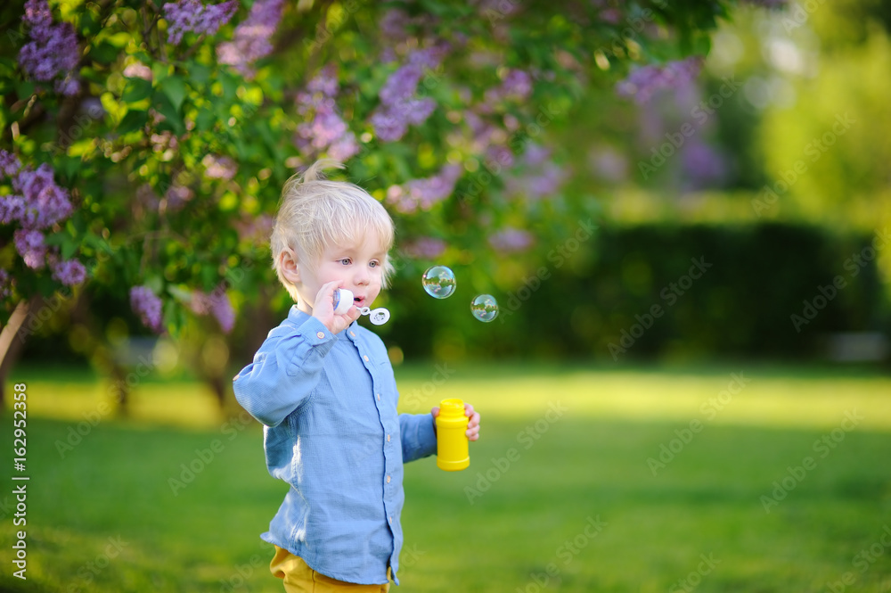 Cute little boy blowing soap bubbles in park Cute little boy blowing soap bubbles in park