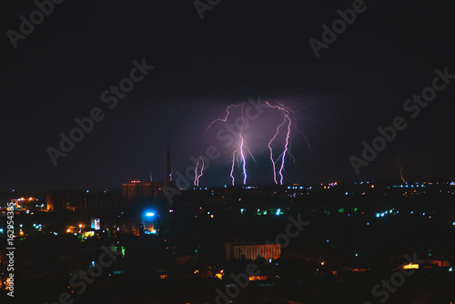 Photo of beautiful powerful lightning over big city  zipper and thunderstorm  abstract background  dark blue sky with bright electrical flash  thunder and thunderbolt  bad weather concept