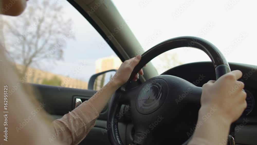Woman driving vehicle in the city. Female hands turning steering wheel. Traffic Woman driving vehicle in the city. Female hands turning steering wheel. Traffic