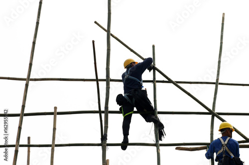 People work on a bamboo scaffold in Hong Kong.  People with unrecognizable faces. 