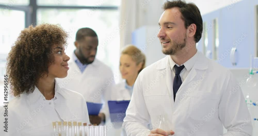 Male And Female Scientists Holding Test Tubes And Flask With Chemicals Talking Working Together In Modern Laboratory Slow Motion 60 Male And Female Scientists Holding Test Tubes And Flask With Chemicals Talking Working Together In Modern Laboratory Slow Motion 60