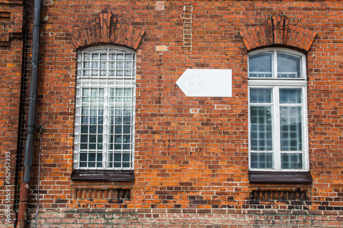 Red brick wall old building with windows and empty copy space white arrow showing direction.