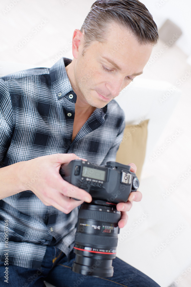 male photographer checking photos in his camera