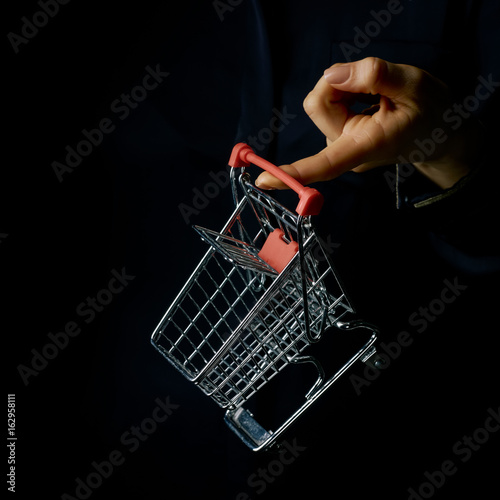 Obraz na plátne woman hand isolated on black showing mall shopping cart