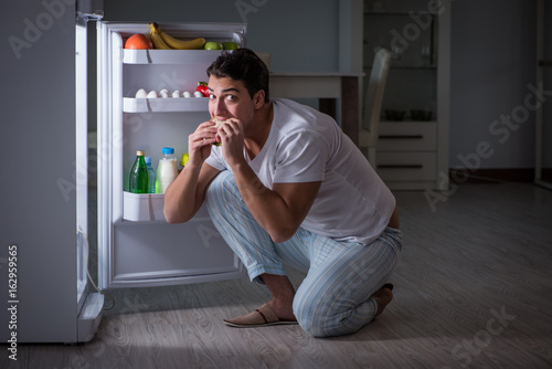 Man at the fridge eating at night