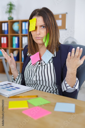 attractive businesswoman at office with post it on her forehead photo