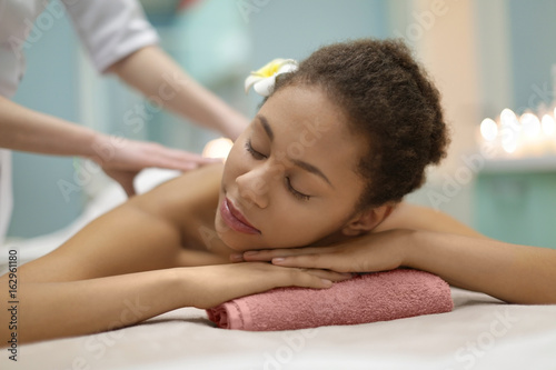 Beautiful African-American girl having massage in spa salon