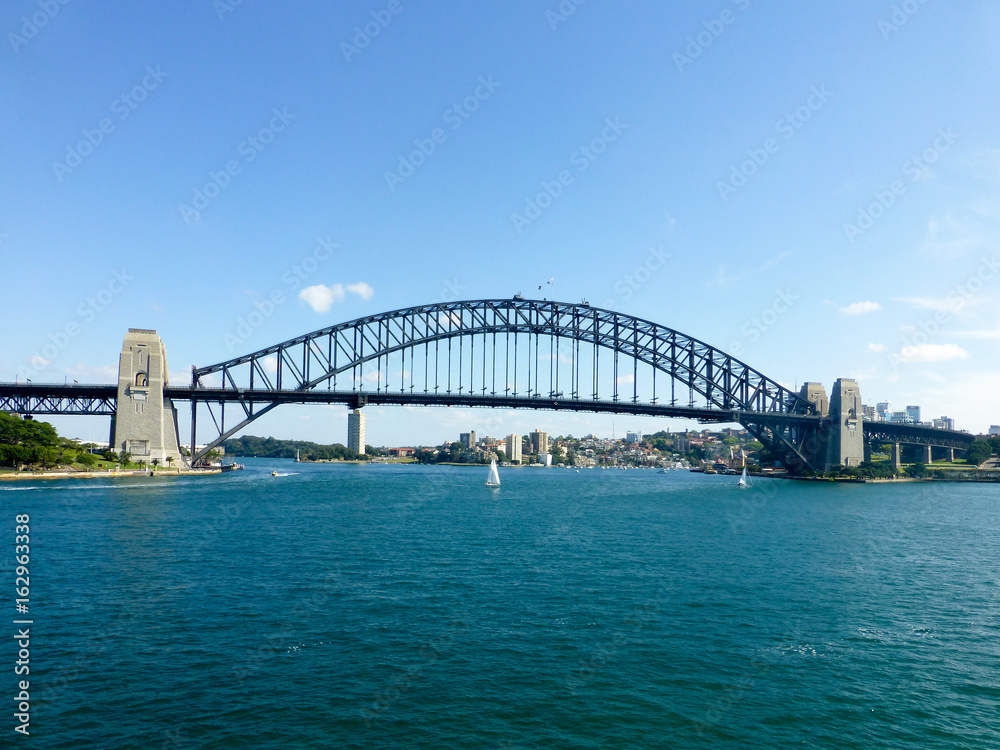 Harbour bridge leading from Syndey on a clear day with sailboats