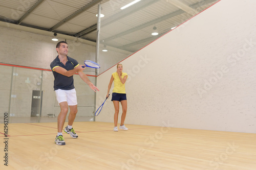 couple playing in indoor tennis court