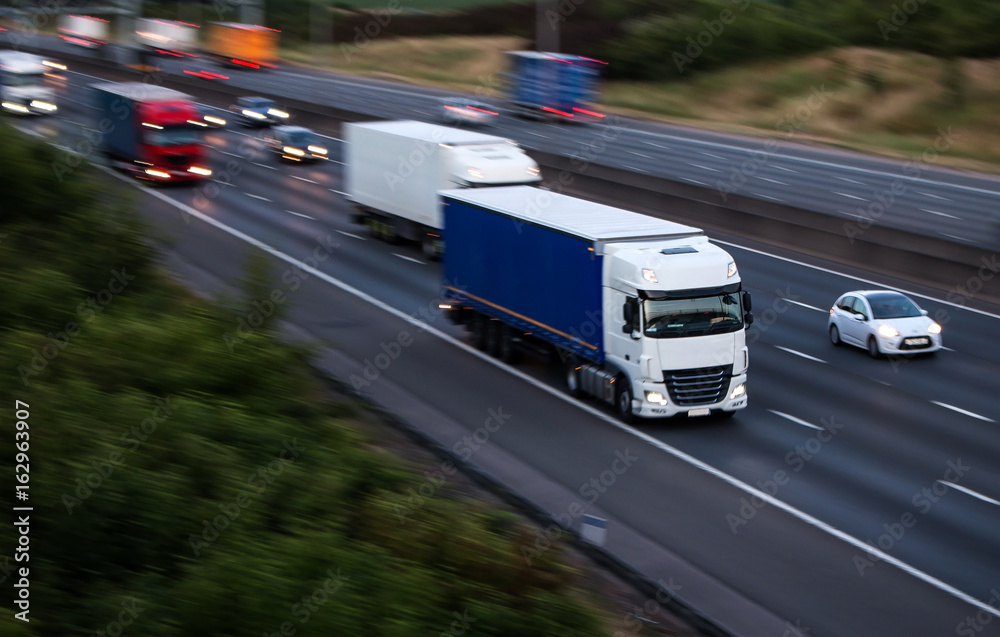 Lorries in motion on the motorway at the dusk time