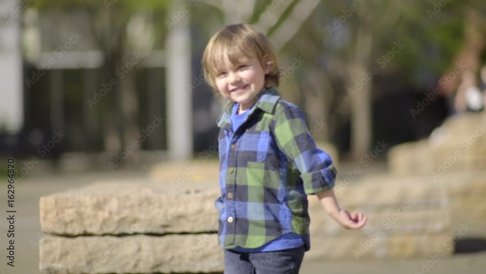 Happy Little Boy Walks Around Rock Sculptures In A City Park, Happy To Explore On His Own Happy Little Boy Walks Around Rock Sculptures In A City Park, Happy To Explore On His Own