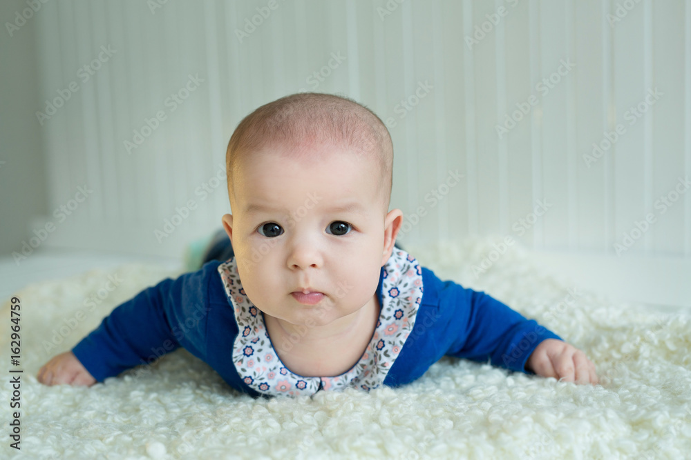 A little European-looking girl with big brown eyes lying on her belly with a keen eye A little European-looking girl with big brown eyes lying on her belly with a keen eye