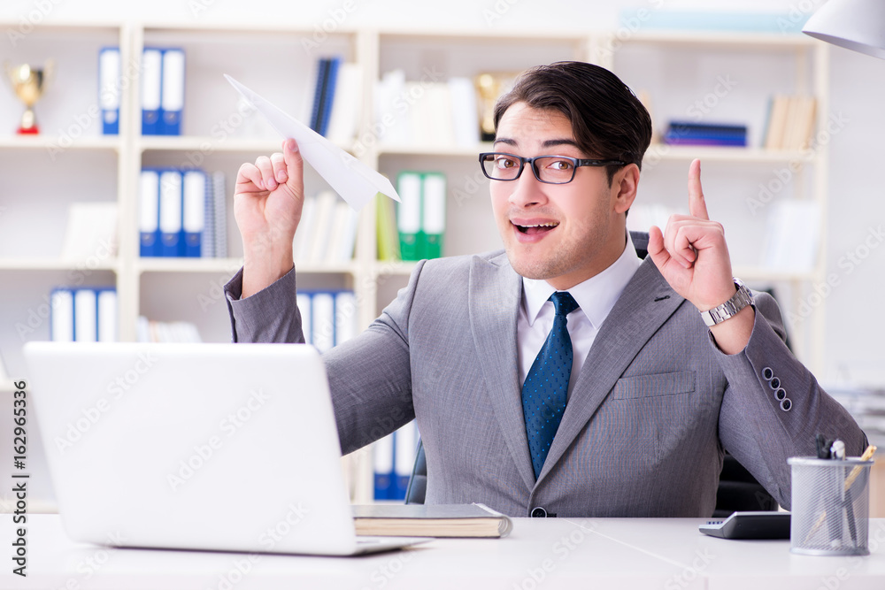 Businessman with paper airplane in office