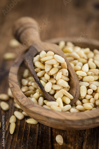 Portion of Pine Nuts on wooden background (selective focus)