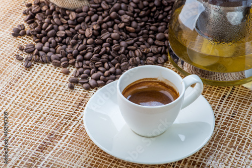 Cup of coffee on coffee beans background on a wooden table