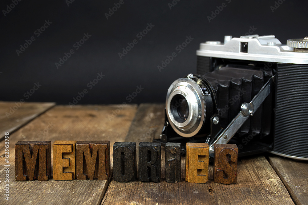 memories text in vintage wooden letterpress type with retro camera on rustic wood