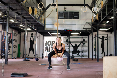 Young attractive woman in gym, exercise with kettlebell