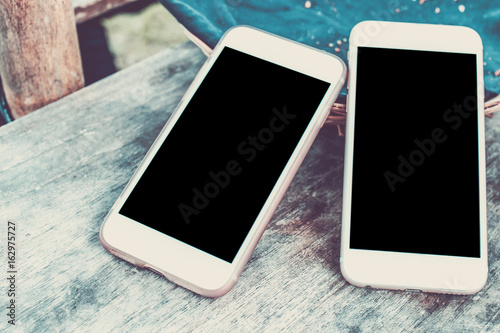 Top view image of two smartphone over wooden table room for text, ready for mockup. Empty space.