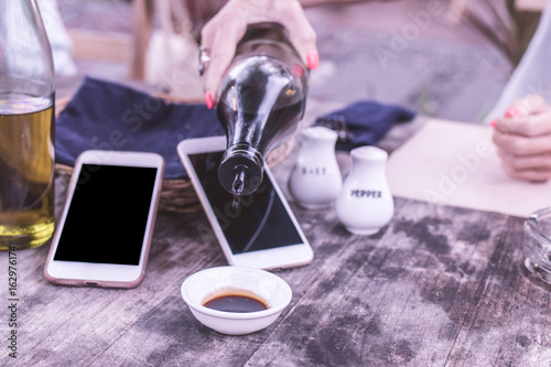 Pouring soy sauce in cafe. Smartphone wit black screen empty space on a background.