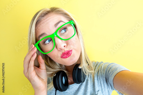 Happy young woman with headphones on a yellow background