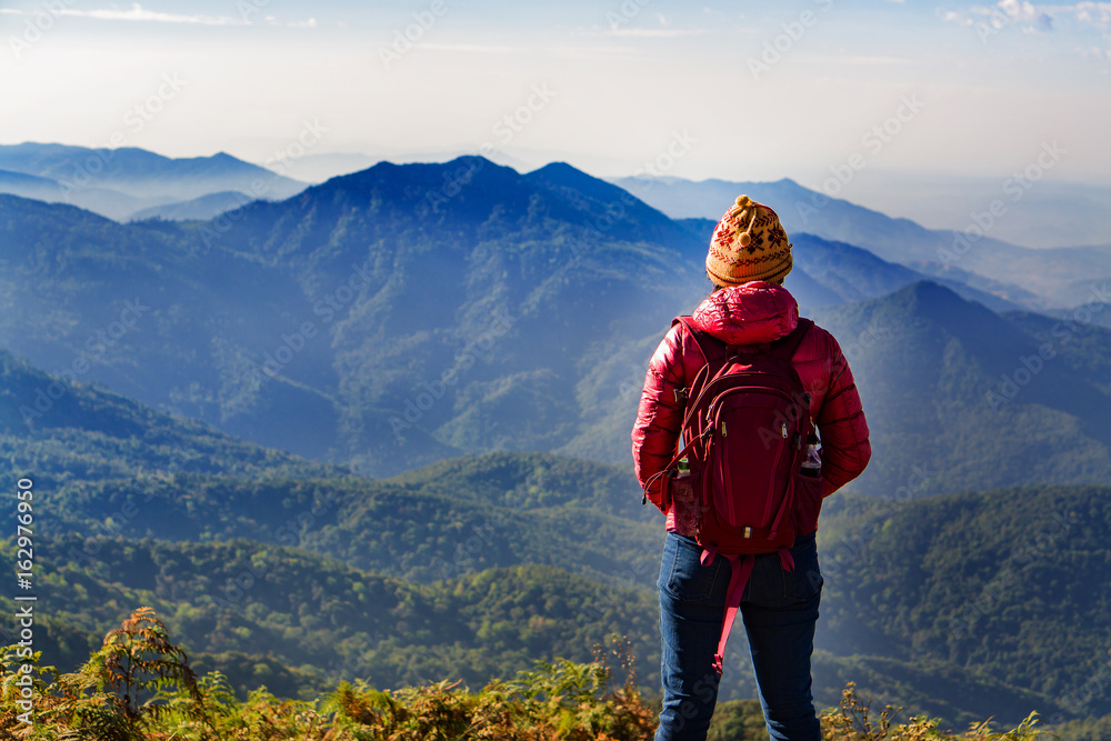 Young woman traveler with backpack standing on the top of the mountain.  Doi Inthanon Chiang Mai Thailand,copy space.
