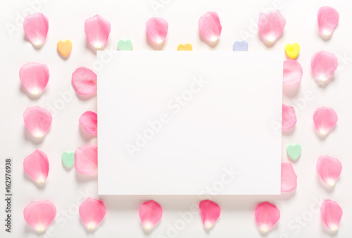 Rose petals and blank white message card aligned on a white background © Tierney