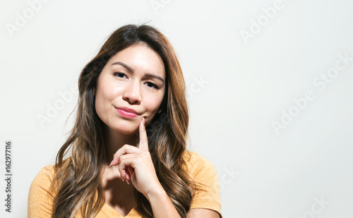 Young woman in a thoughtful pose on a off white background