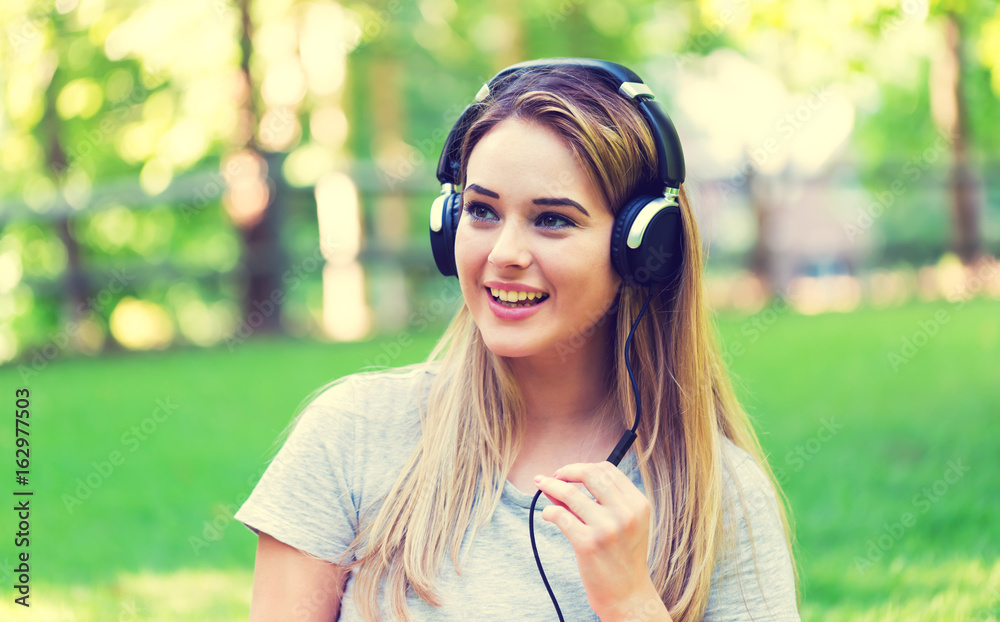 Young woman with headphones outside on a summer day Young woman with headphones outside on a summer day