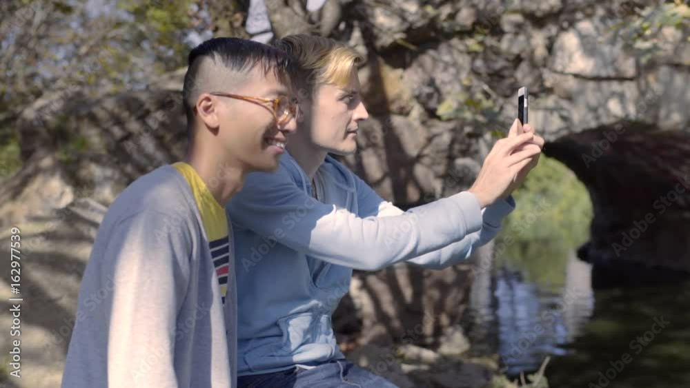 Closeup Of Gay Couple, Man Takes Panorama Photo Of Pond, Then A Selfie With His Boyfriend Closeup Of Gay Couple, Man Takes Panorama Photo Of Pond, Then A Selfie With His Boyfriend