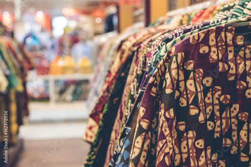 Clothes hang on a shelf in a shopping mall on Bali island, Indonesia. Indonesian cotton batik.