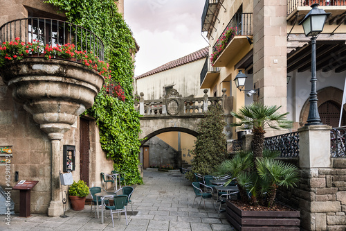 Fototapeta Naklejka Na Ścianę i Meble -  Traditional old Spanish street with beautiful balconies and arches in Barcelona town, Spain 