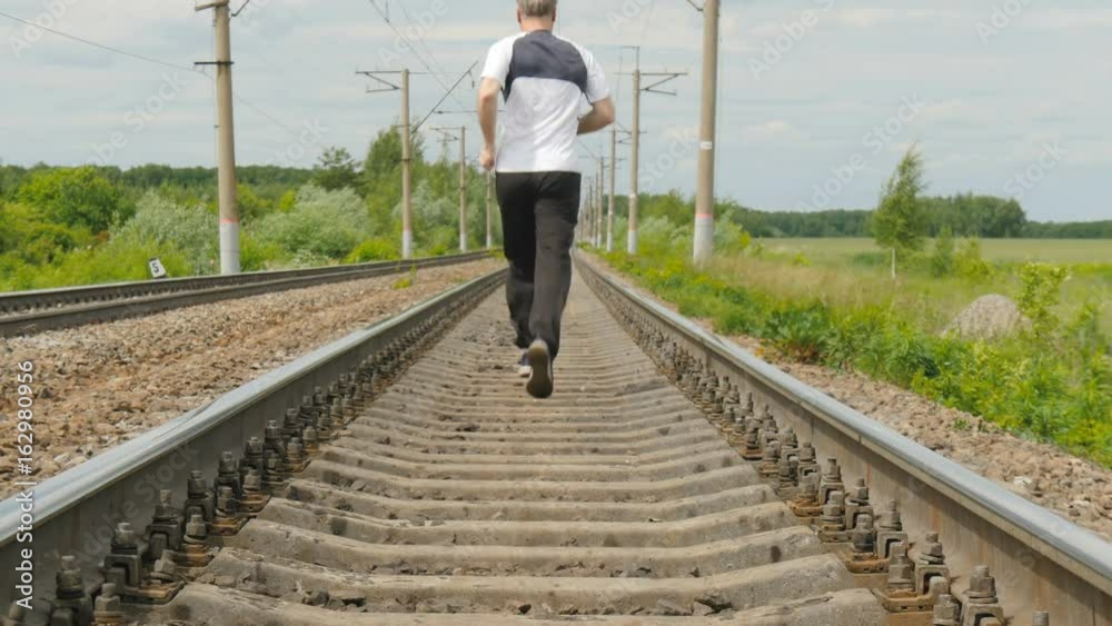 A man in sports uniforms runs on rails. He follows his health, runs cross, active life style. A man in sports uniforms runs on rails. He follows his health, runs cross, active life style.
