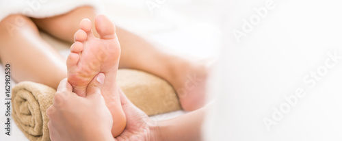Professional therapist giving traditional thai foot massage to a woman