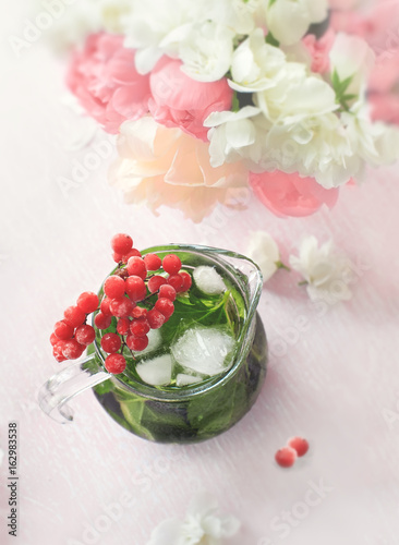 Fototapeta Naklejka Na Ścianę i Meble -  Cooling mint detox water with a branch of viburnum and a bouquet of pink and white peonies on pastel pink background.