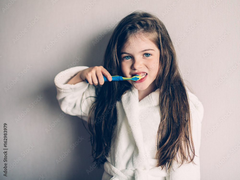 Little cute girl in a bathrobe brushing her teeth Little cute girl in a bathrobe brushing her teeth