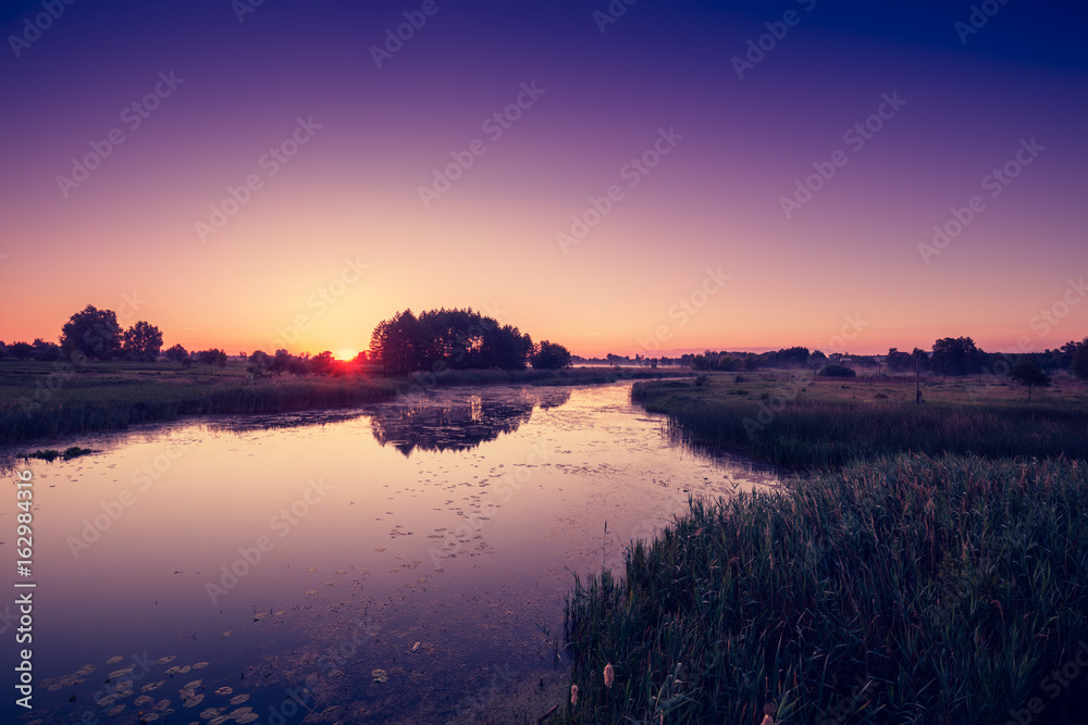 Magical pink purple sunrise over the river. Misty morning, rural landscape, wilderness, mystical feeling