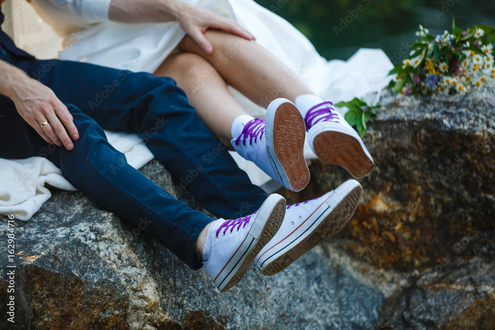 Love story told by boots. Human feet close up. Man and woman in sneakers.  Girl in white shoes. Guy in black sneakers and denim. Hipster couple in  summer. Legs close up. Photos