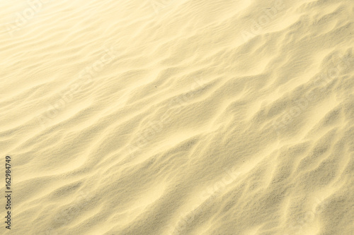 Golden glitter on blurry sand background