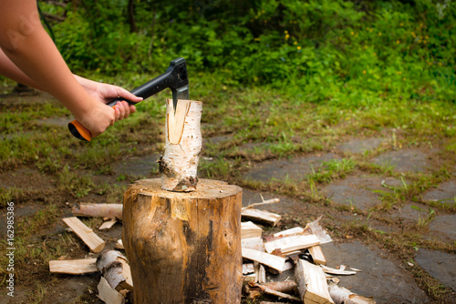 Young man with axe chopping wood on a chopping block