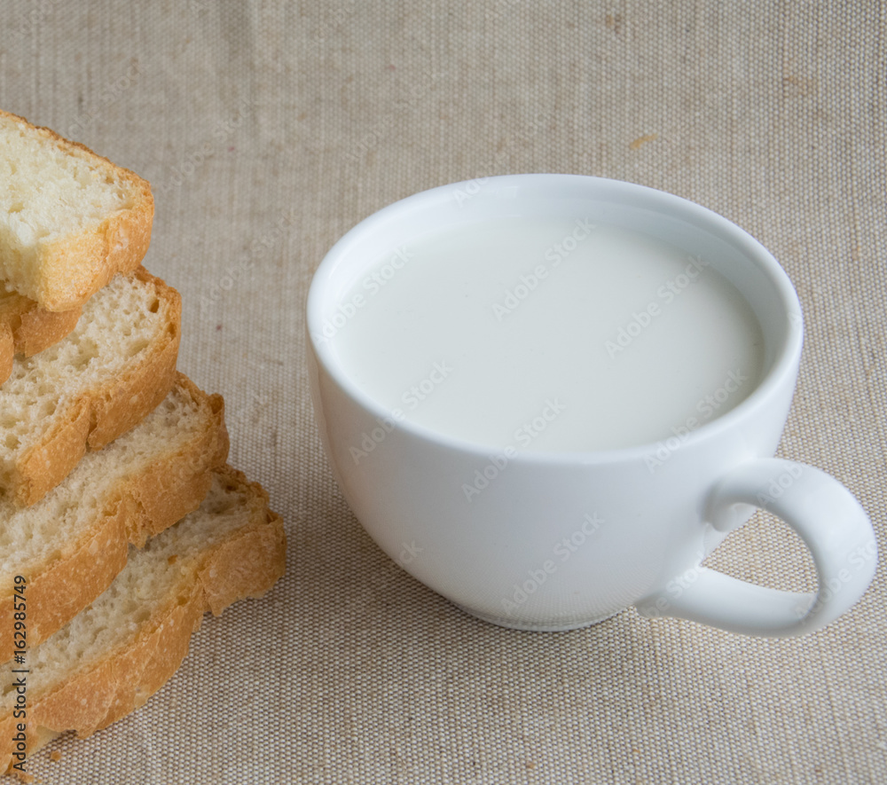 A cup of milk and pieces of white bread. A cup of milk and pieces of white bread.
