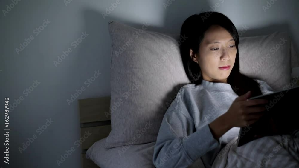 Woman working on digital tablet at night