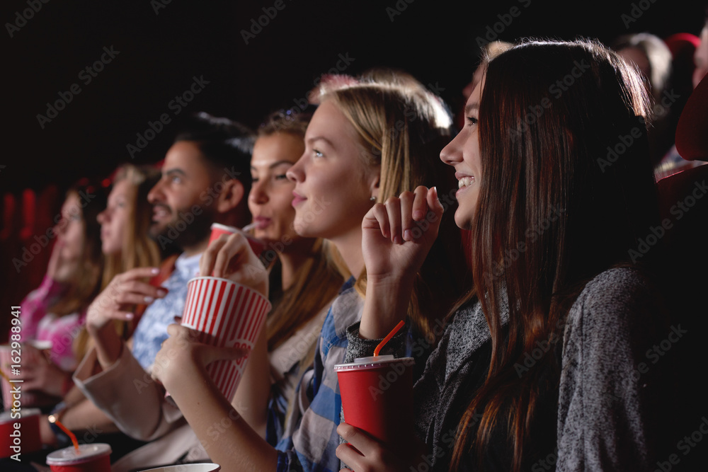 Group of female friends laughing and smiling watching a film together at the movie theatre snacks popcorn entertainment people lifestyle leisure friendship concept. Group of female friends laughing and smiling watching a film together at the movie theatre snacks popcorn entertainment people lifestyle leisure friendship concept.